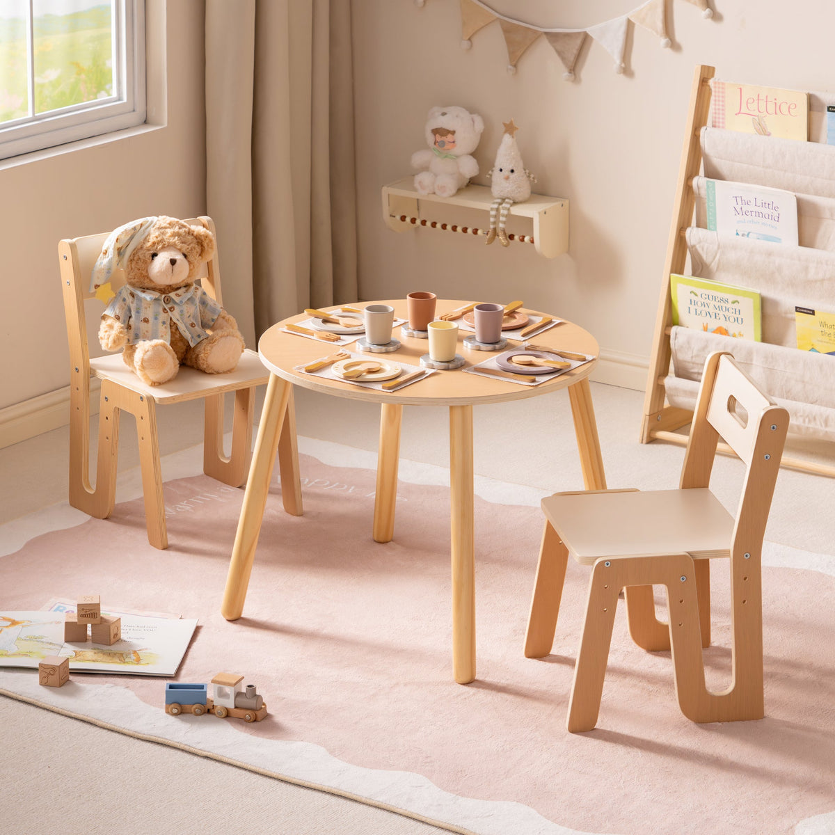 Natural wood ROBUD Glowwood table and chairs with toy dishes laid out and a bookshelf visible in the sunlit room.