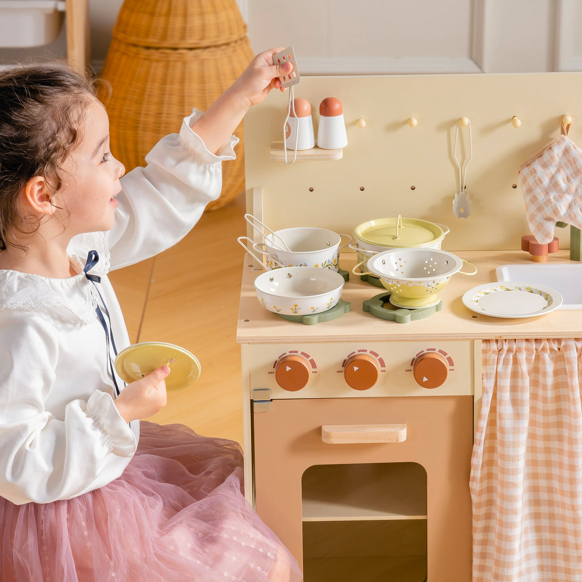 Girl in chef hat arranging food on pink plates at wooden ROBUD Tinplate Pretend Cooking Utensils play kitchen with accessories on counter