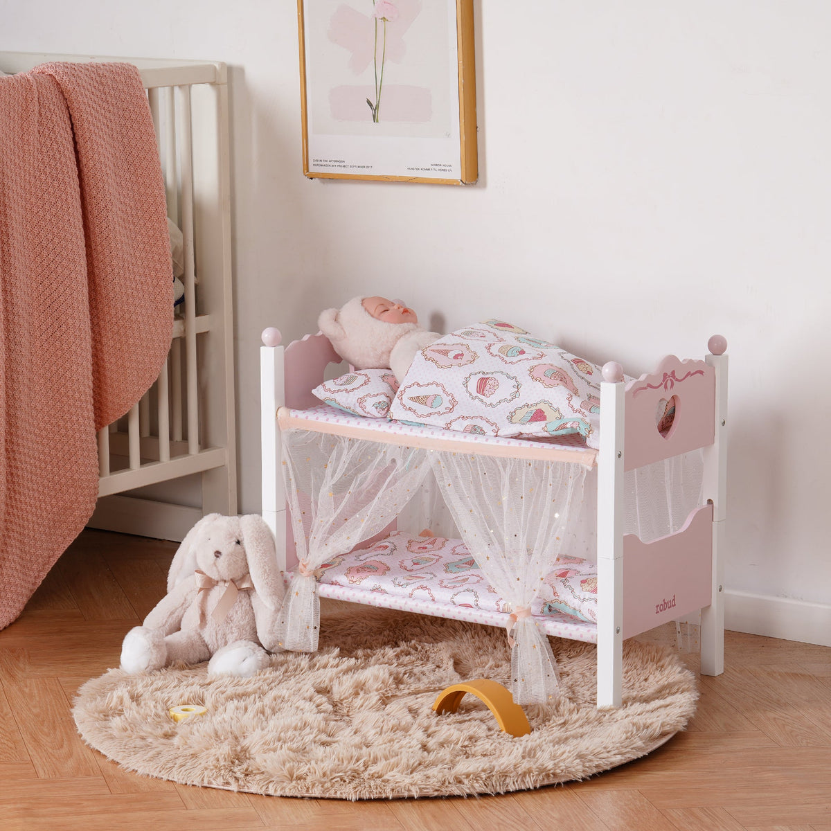 ROBUD white wooden doll bunk bed with sheer star canopy on the top bunk, styled in a warm pastel-toned nursery corner.