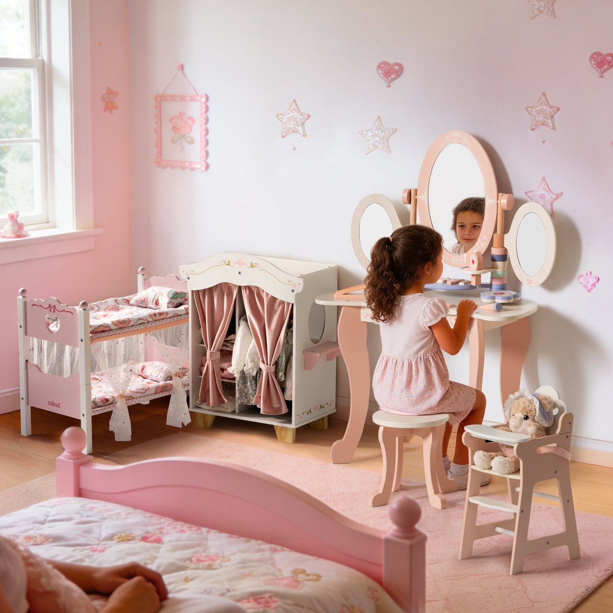 Young girl seated at a ROBUD triple-mirror vanity playing makeup in a pink room with doll bunk bed and wardrobe nearby.