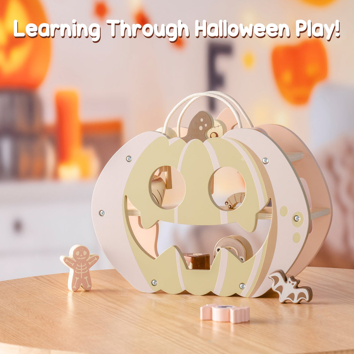 ROBUD Halloween Candy House pastel pumpkin toy on wooden table glowing warmly beside real pumpkin lanterns in a Halloween-decorated room