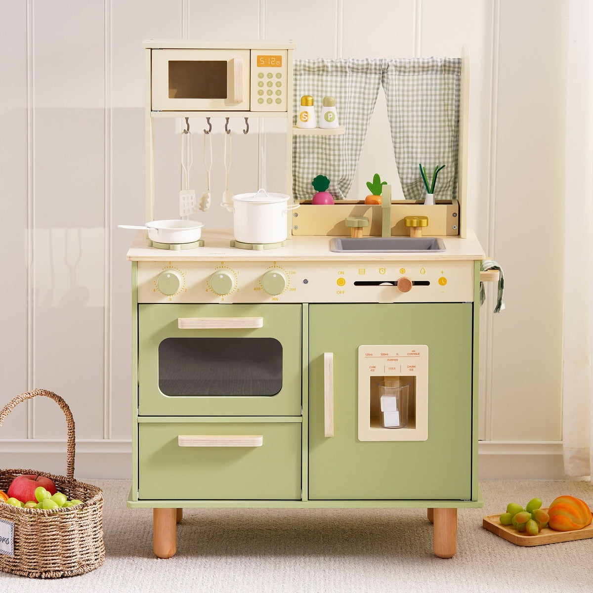 ROBUD sage green wooden play kitchen displayed with a wicker fruit basket nearby in a warm, naturally lit playroom setting.