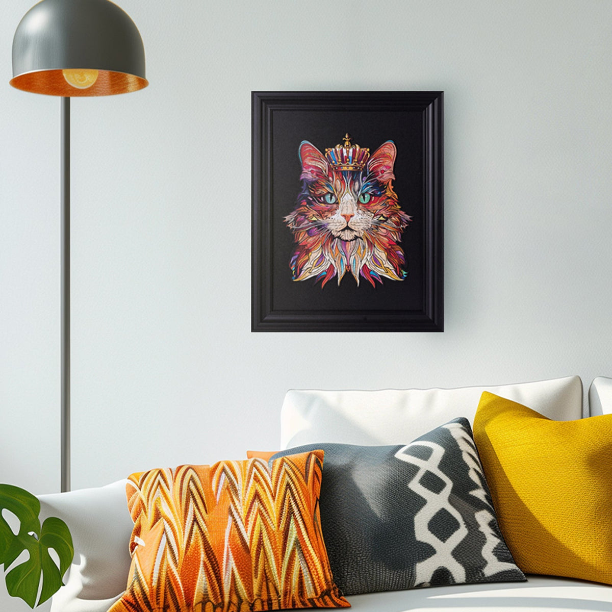 Rowood Cat King wooden puzzle displayed in a black frame on a wall in a modern living room above a white sofa with orange and yellow cushions.