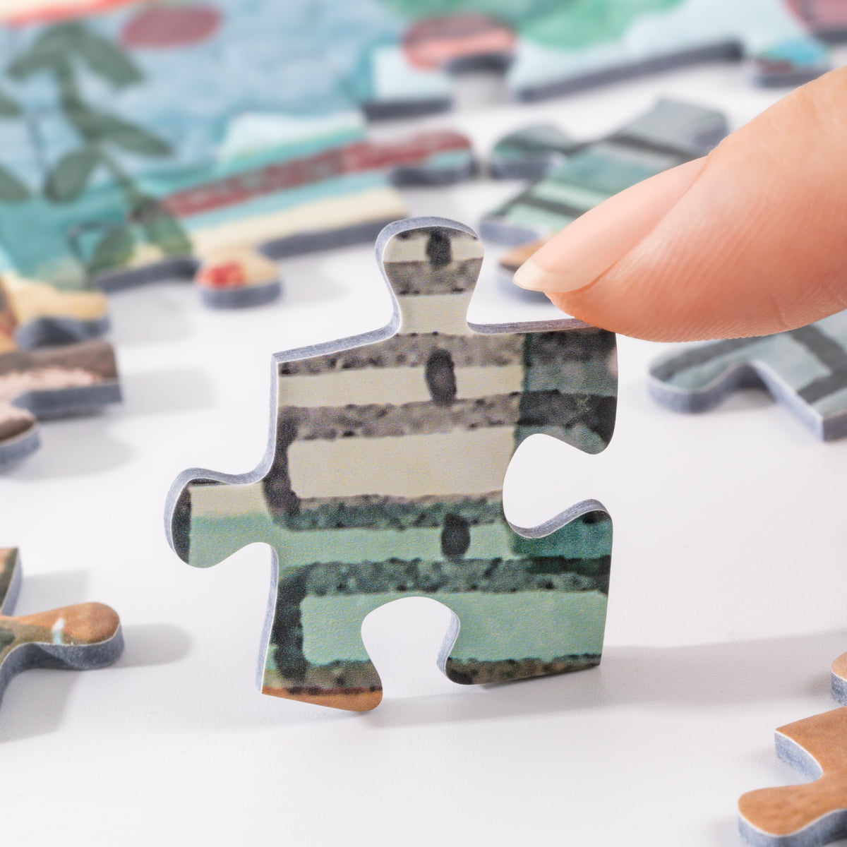 Close-up hand placing a Rolife Leisure in Paris PT004 puzzle piece showing muted green and grey illustrated building tones