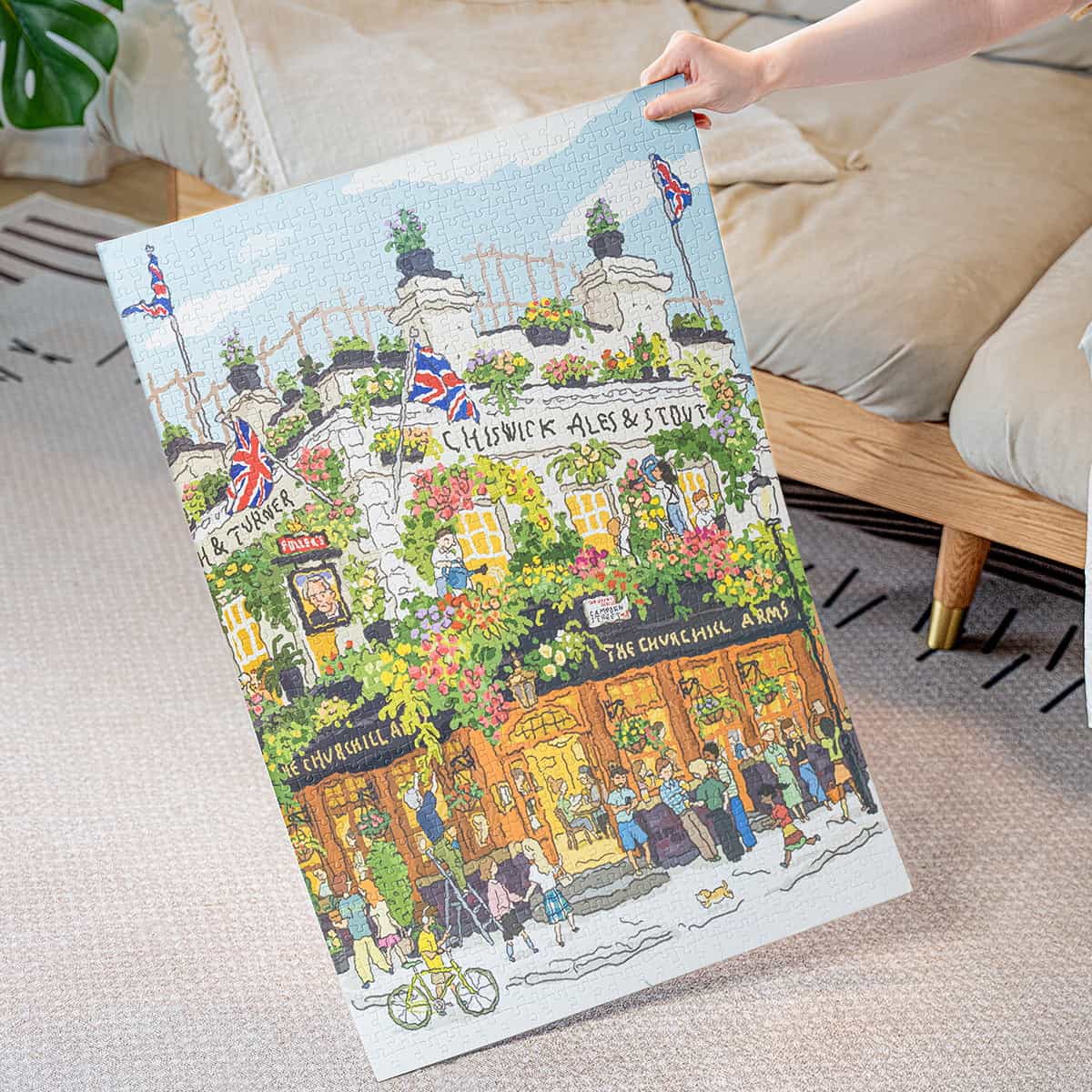 Person holding up completed Rolife Pub in London PT007 jigsaw puzzle showing illustrated colorful flower-covered pub facade