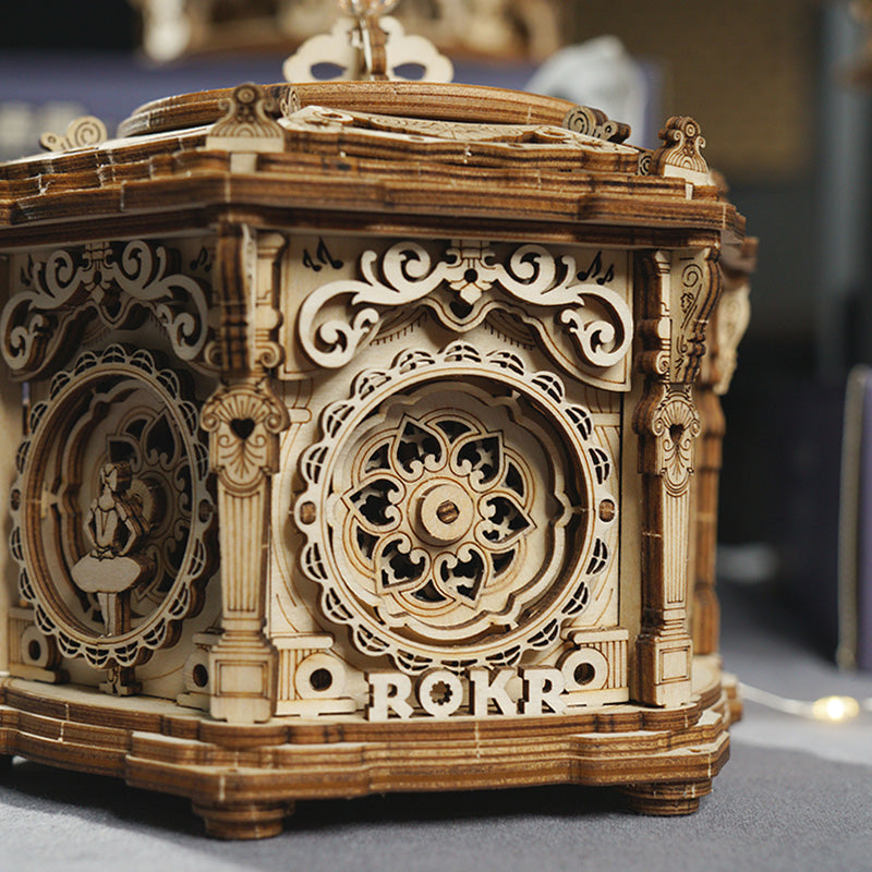 ROKR Secret Garden music box front view showing ROKR logo panel with ornate carved motifs on golden brown wood