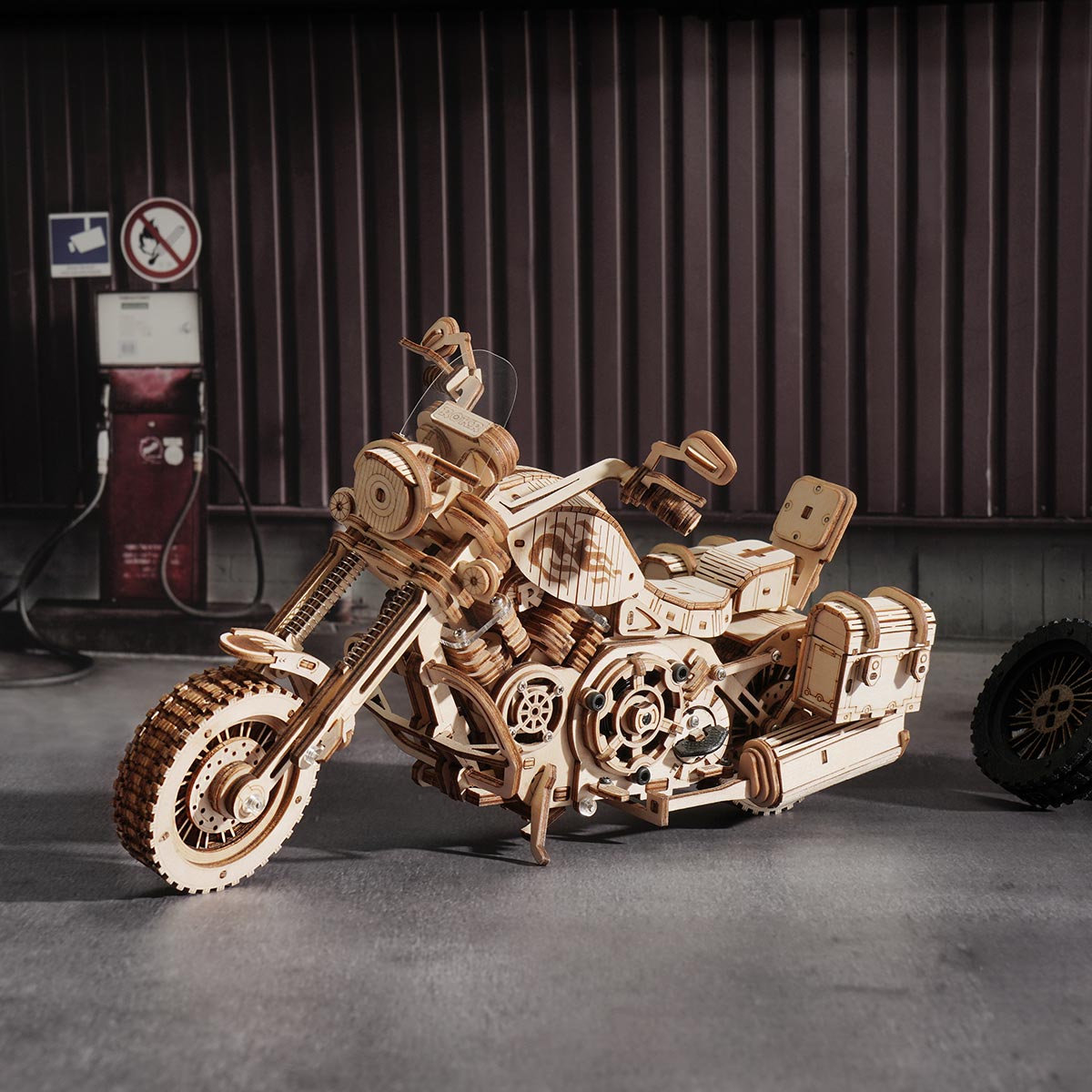 ROKR Cruiser Motorcycle wooden model displayed in a dark garage scene beside a vintage fuel pump