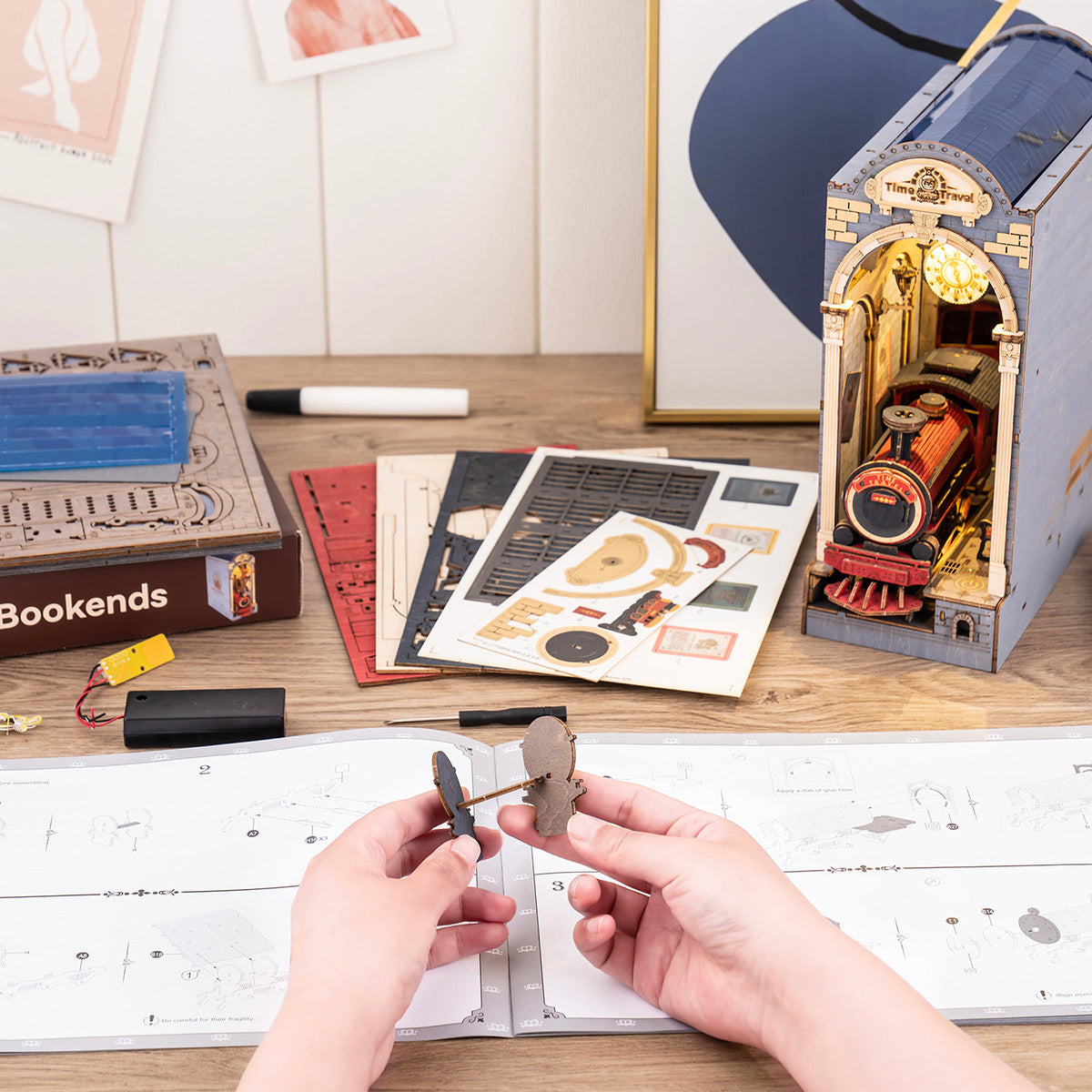 Hands assembling Rolife Time Travel book nook with parts, craft pen and instruction sheets on desk