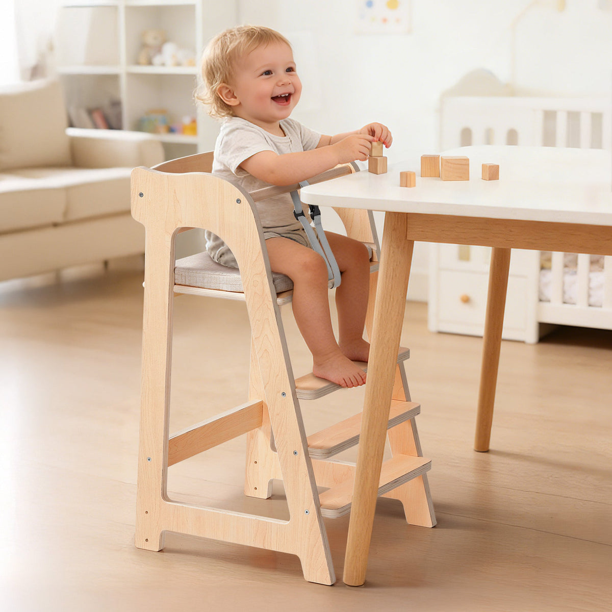 Cheerful toddler sits in a ROBUD solid wood high chair with building blocks on the tray in a bright modern home.