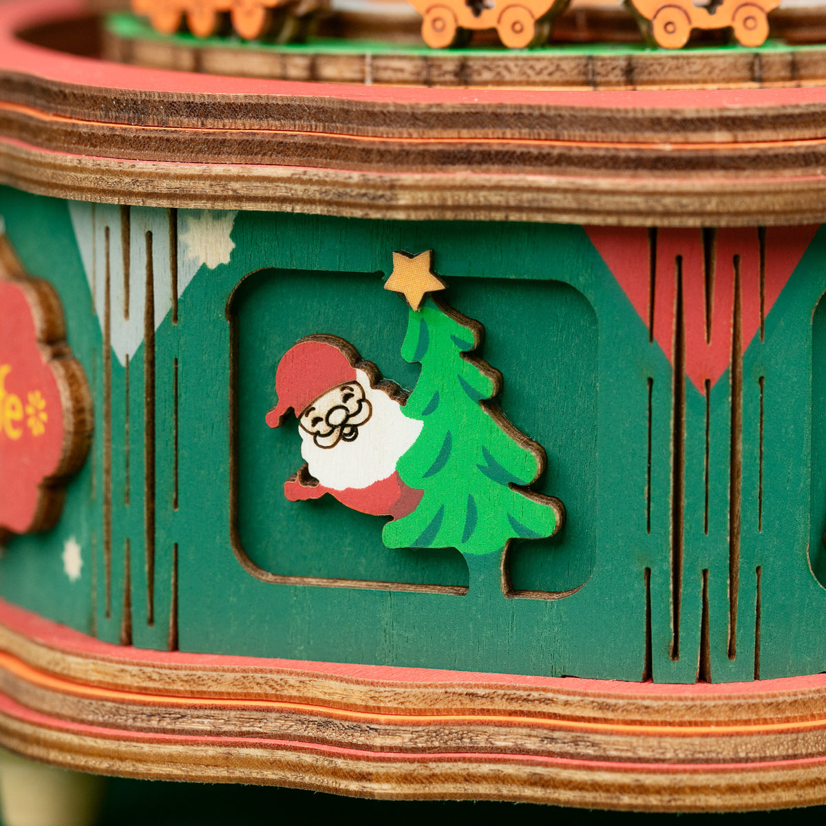 Close detail of a green music box base with a Christmas tree and red trim.