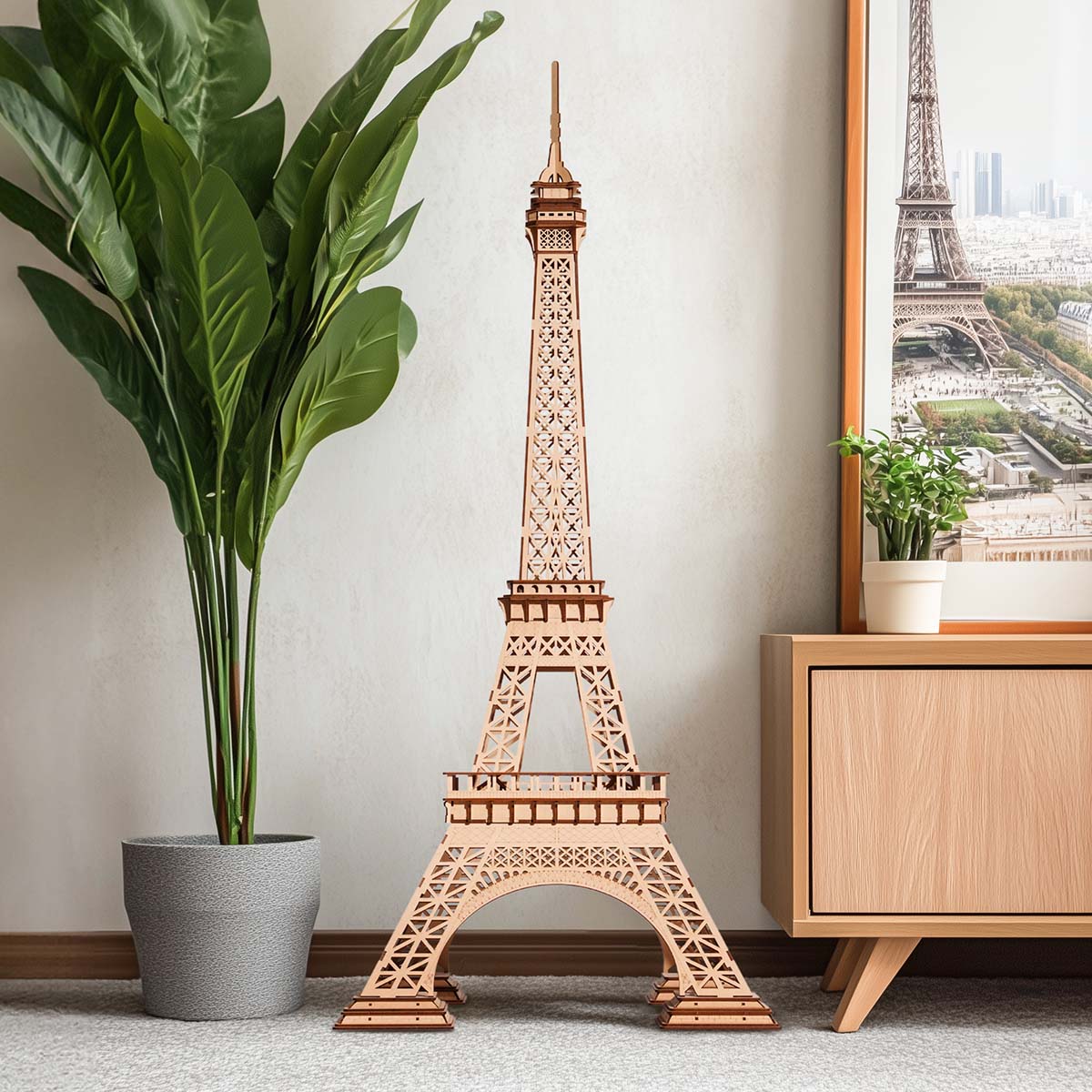 Rolife Eiffel Tower Plus wooden model displayed near a potted plant and framed wall art.