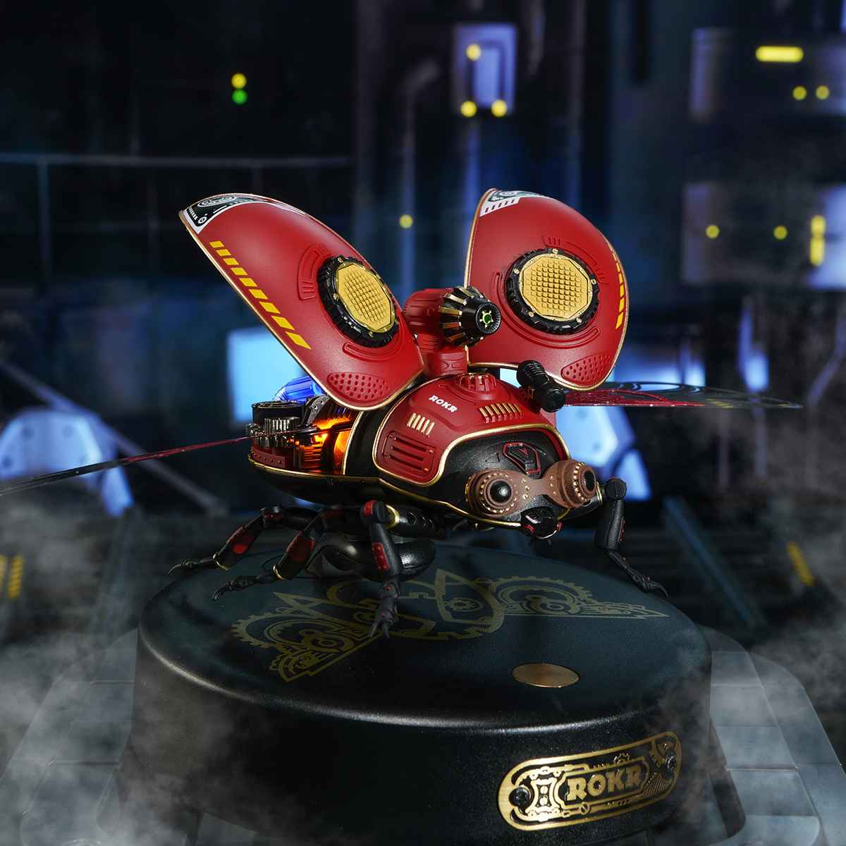 ROKR Scout Beetle 3D mechanical puzzle on branded circular base, red and gold insect body glowing under studio lighting
