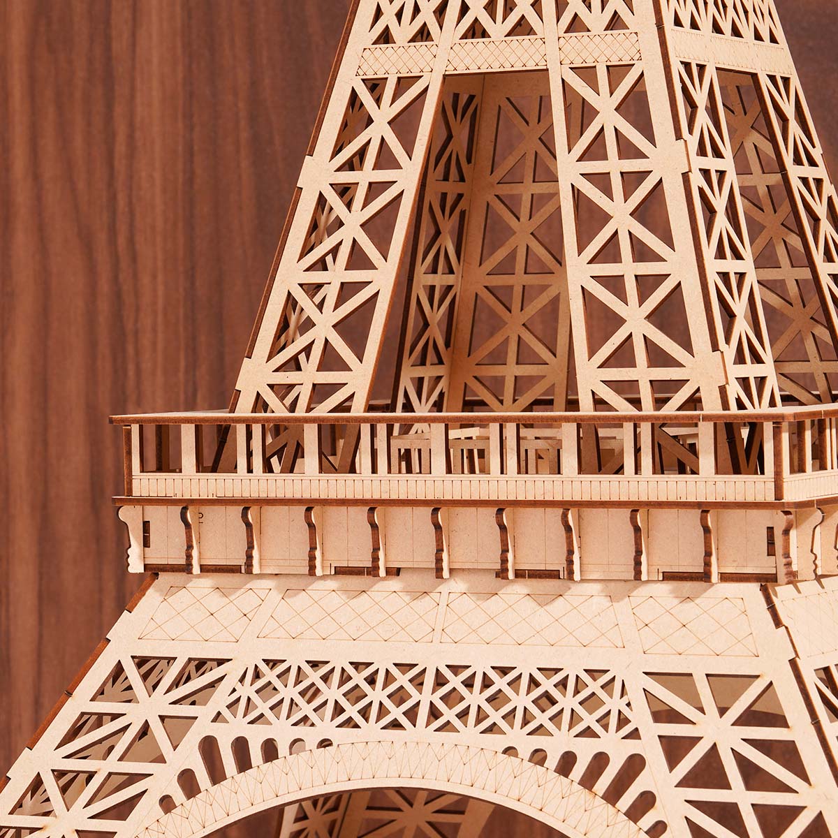 Close detail of the Eiffel Tower wooden model base with layered lattice and railings.