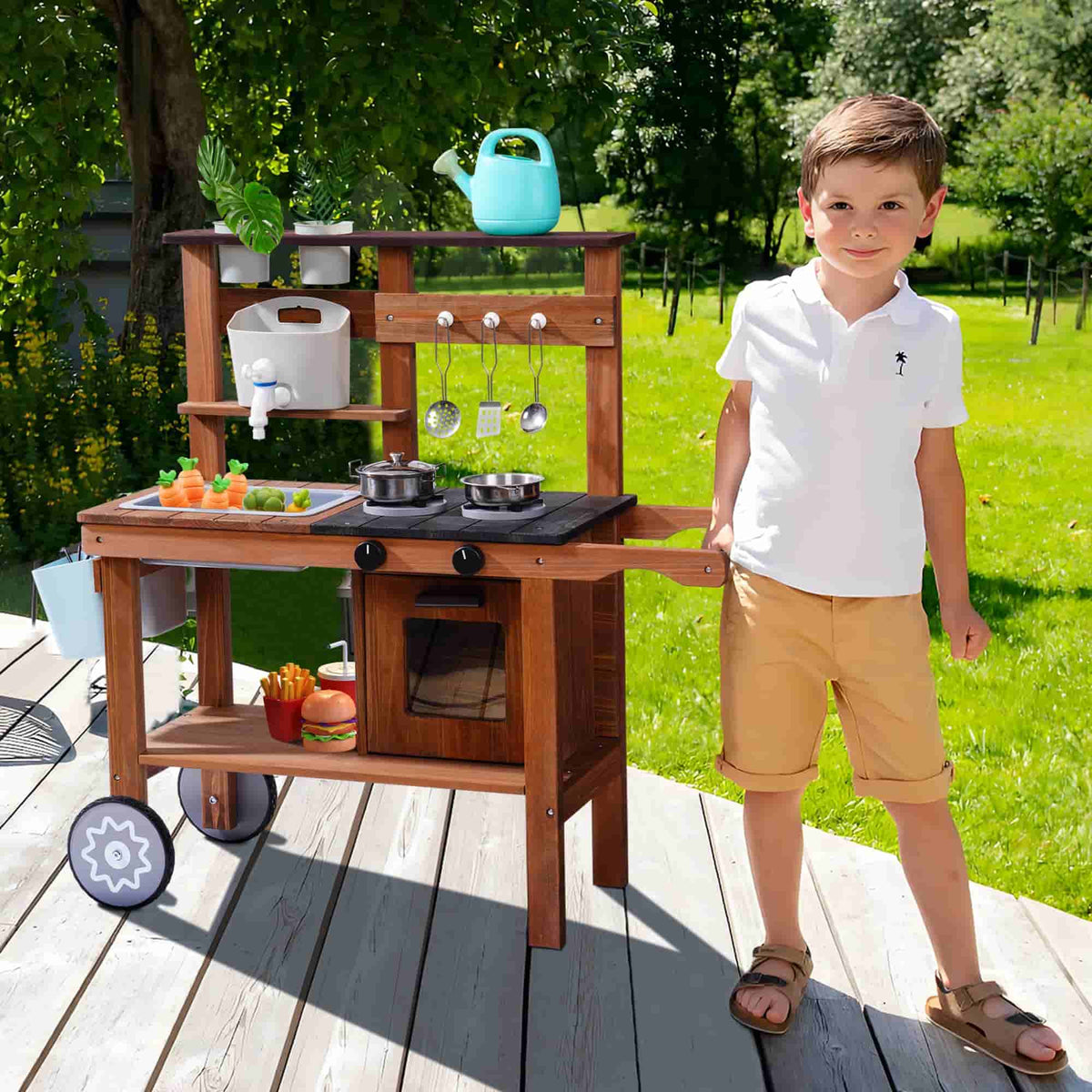 Boy in white shirt playing with a ROBUD outdoor wooden mud kitchen on wheels in a sunny garden setting