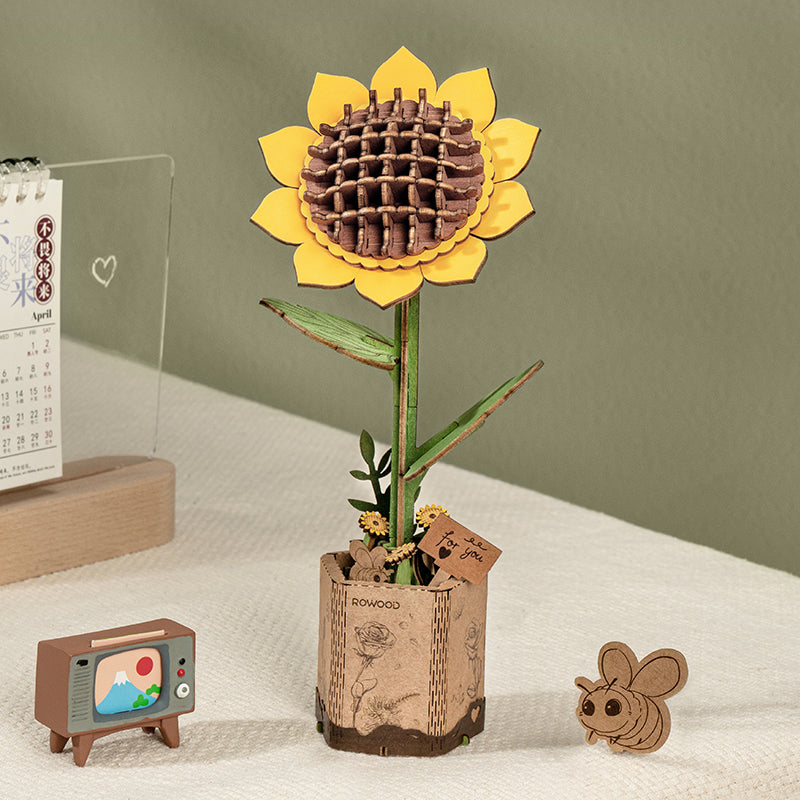 Die Rowood Holz-Sonnenblume steht in einem Pflanzgefäß im Papiertüten-Stil, daneben kleine Schreibtischdekorationen.
