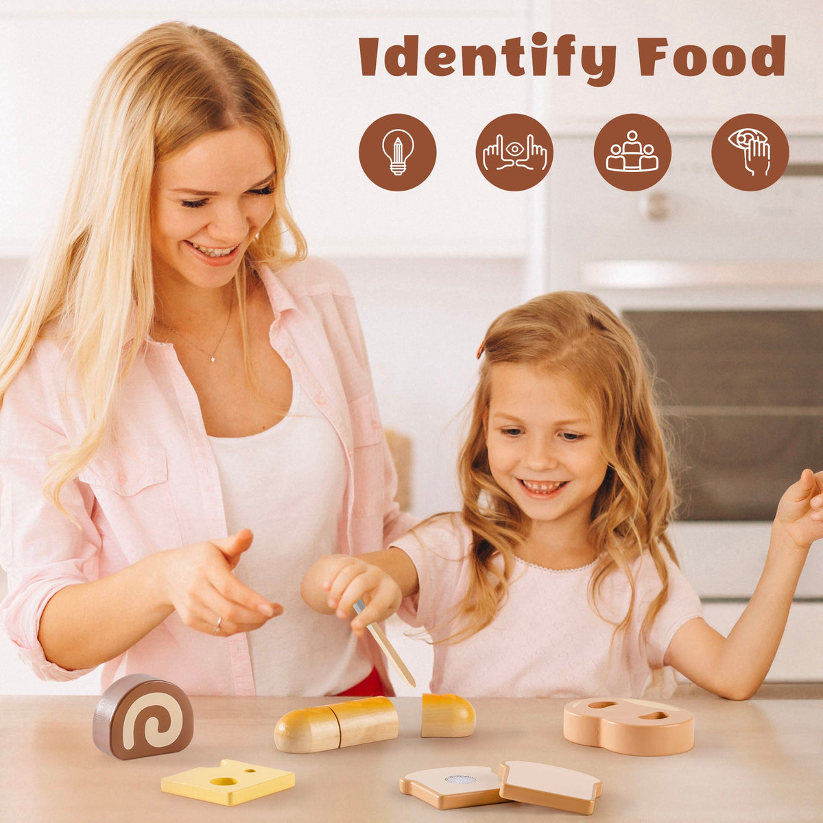 Mother and daughter at a kitchen counter identifying wooden dessert pieces from the ROBUD bread playset including swiss roll, baguette, toast, and pretzel