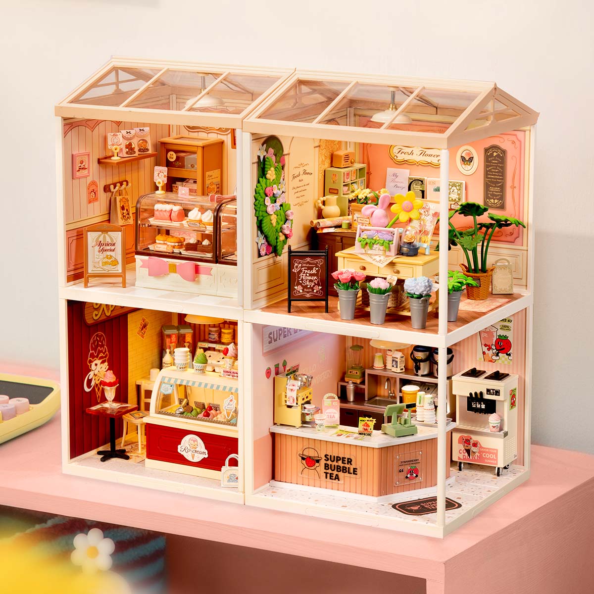 Rolife Super Creator 4-in-1 Four Grid pink dollhouse showing a bedroom and bathroom on the top floor and a cozy kitchen and living room on the bottom floor