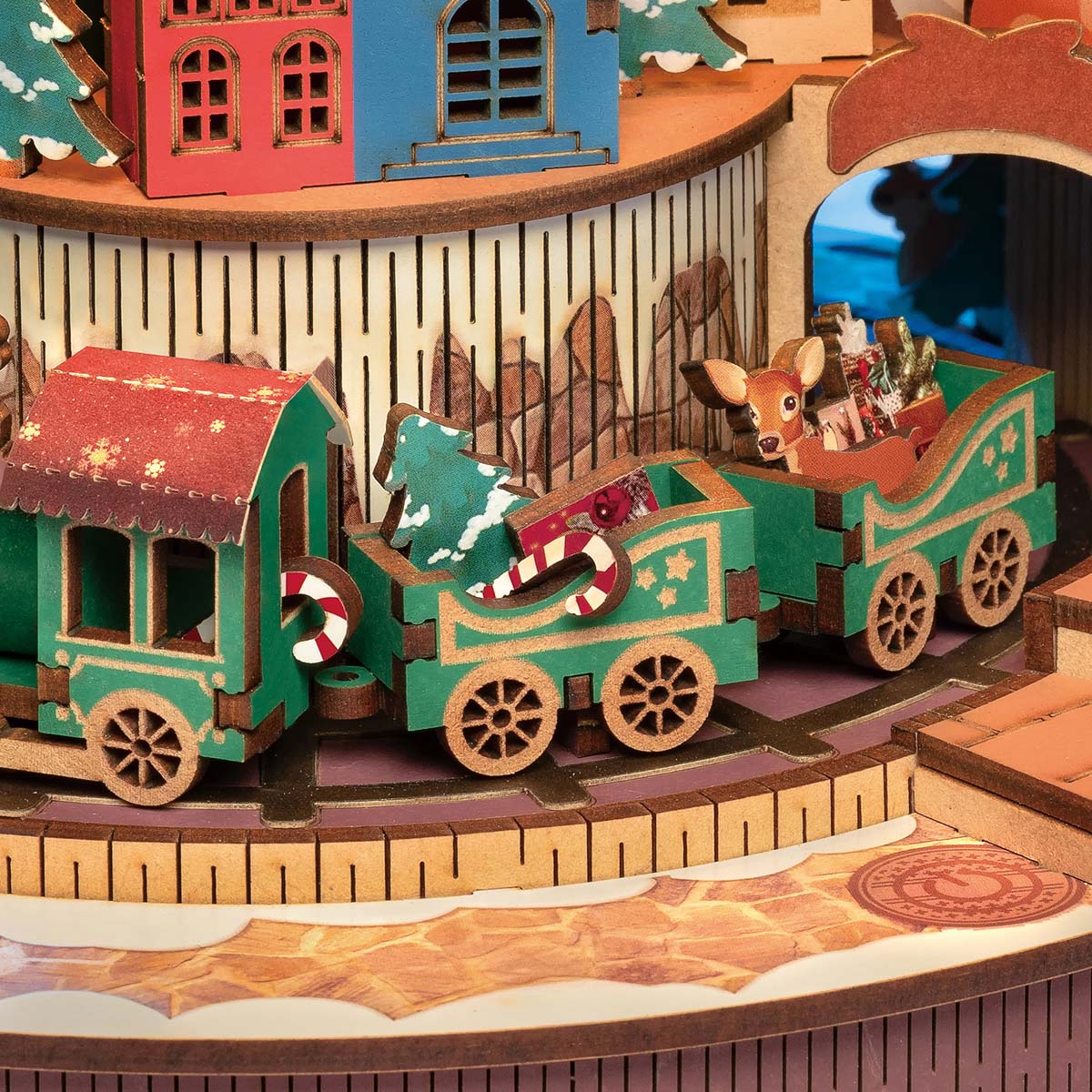Rolife Christmas Melody Tree AMS01 detail view of the green miniature train circling a candy cane platform beneath colorful Christmas village buildings