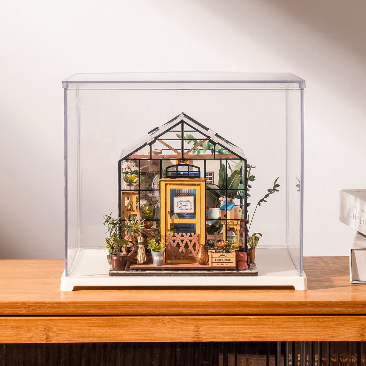 Rolife Cathy's Flower House rests inside a clear display box on a white tabletop.