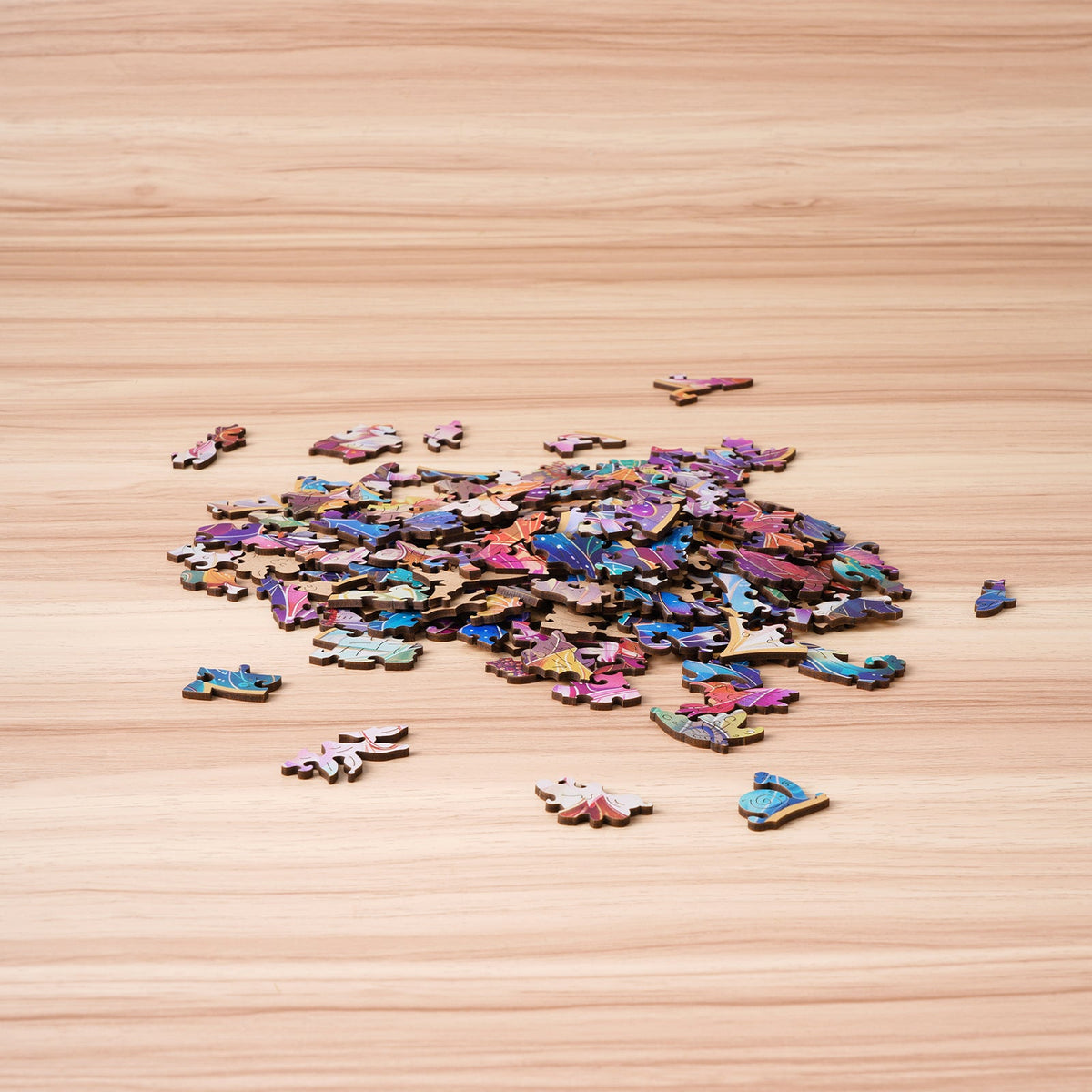 Rowood Mystic Mandala Flower wooden puzzle pieces spread across a light wooden surface before assembly with colorful petal shapes visible.