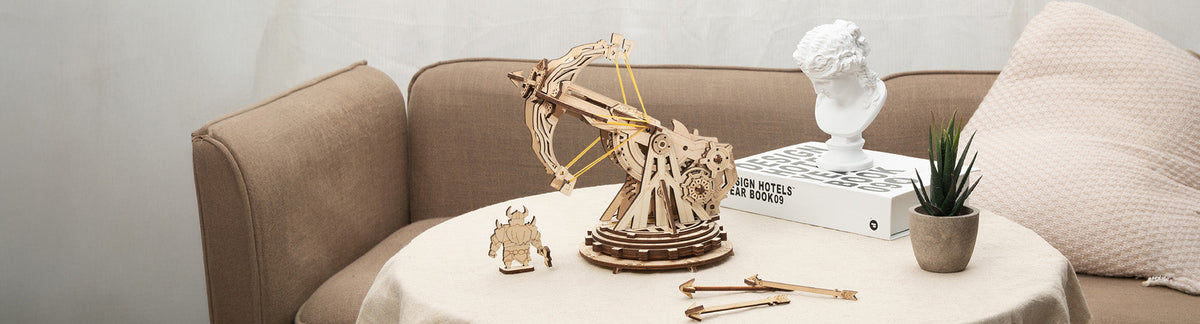 ROKR Epic War crossbow KW401 PC banner, natural wood siege crossbow with elastic string on a round table beside a warrior figure and arrows