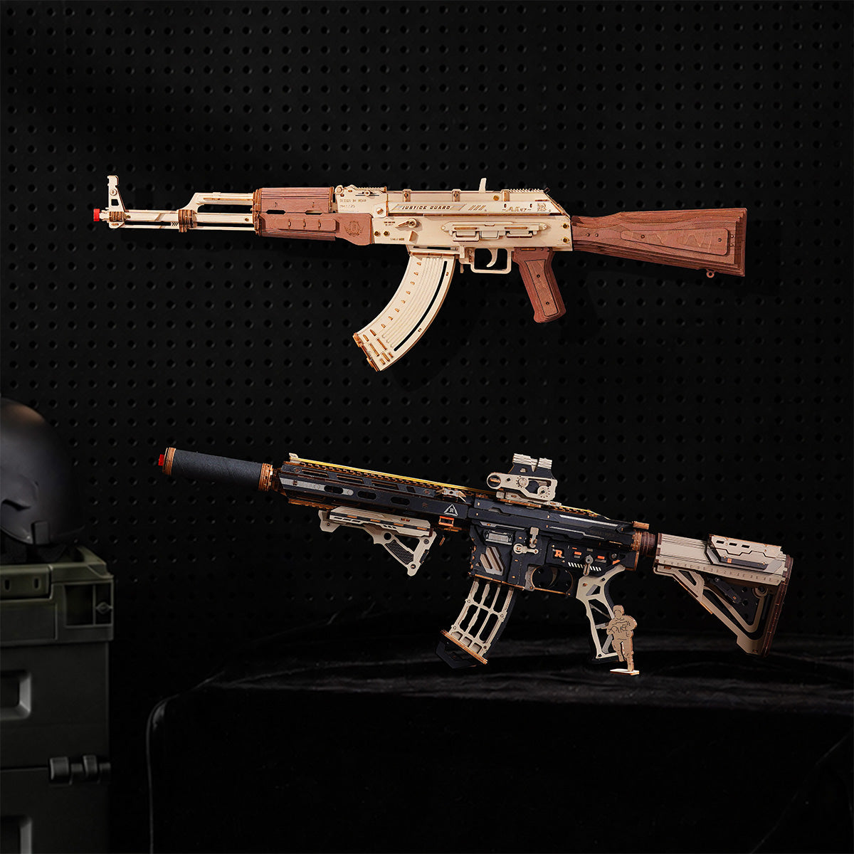 Two wooden puzzle rifles mounted on a black pegboard, a light wood AK style model above a black and tan modern rifle.