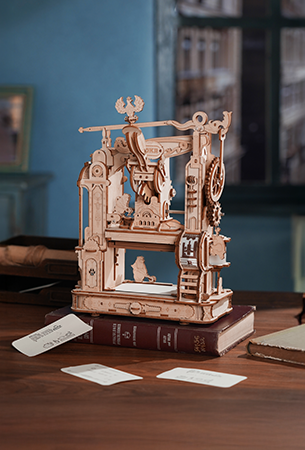 Robotime Mechanical interest category tile, ROKR wooden printing press model on a desk with old books and cards