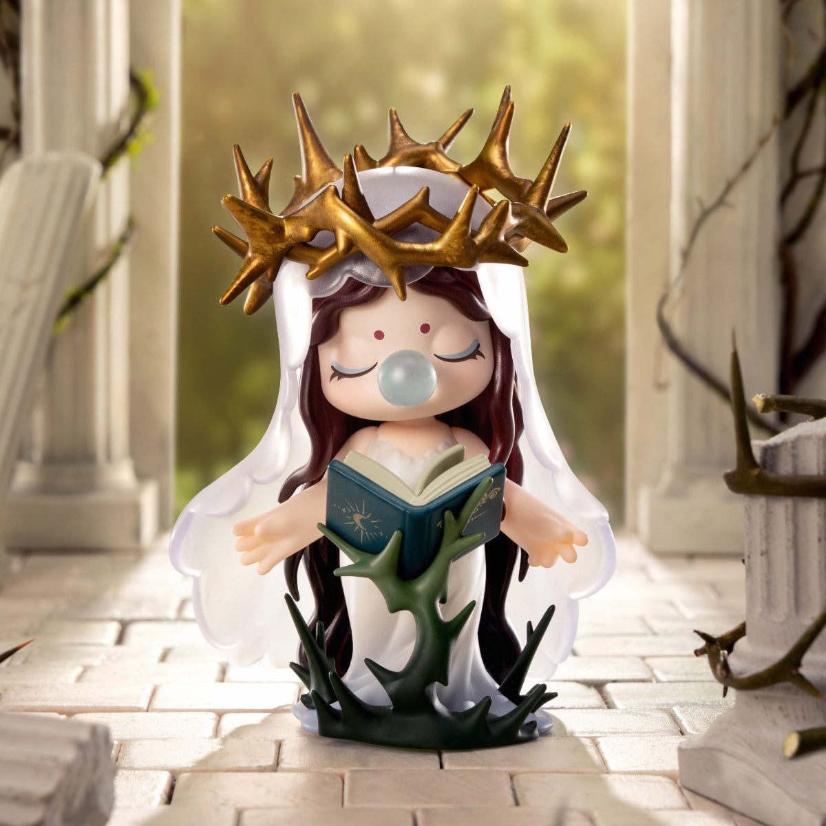 Figurine wearing a golden thorn crown and holding an open book, standing among stone columns and ivy
