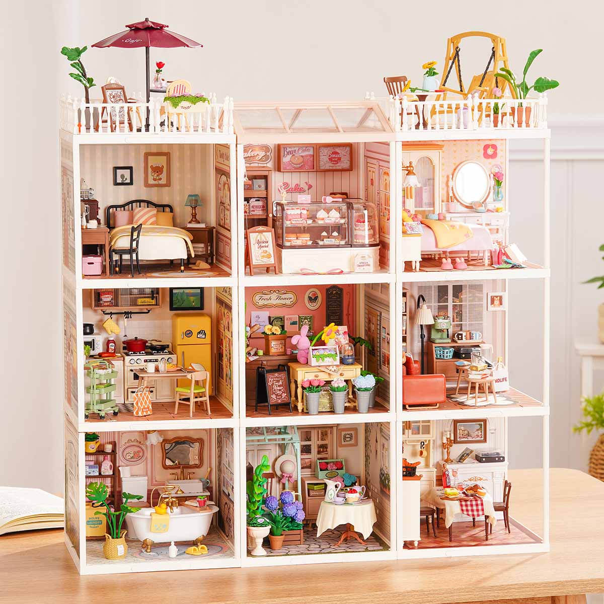 Rolife Super Creator Series 9-in-1 Nine Grid miniature dollhouse set with nine furnished rooms including bedroom, bakery, and flower shop displayed on a wooden table.