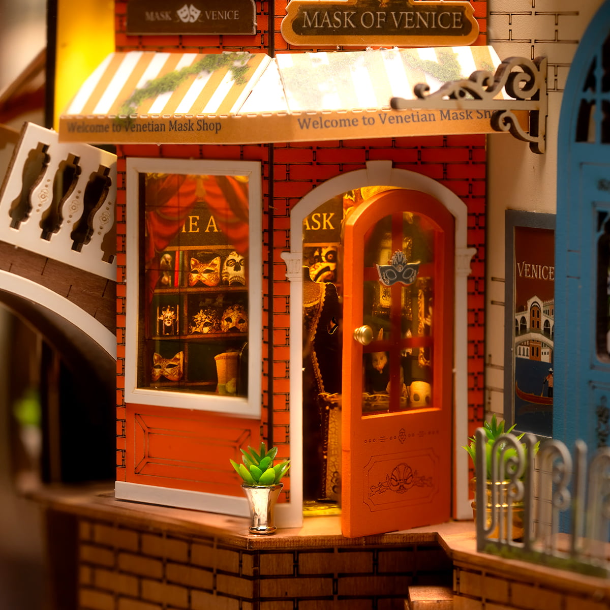 Rolife Romantic Venice TGB08 Book Nook displayed on wooden bookshelf between books showing full illuminated gondola canal scene with warm glow