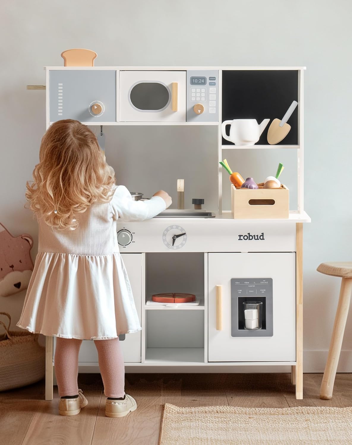 Robud play kitchen rear view of a toddler girl in white dress pretending to cook at the wooden stove