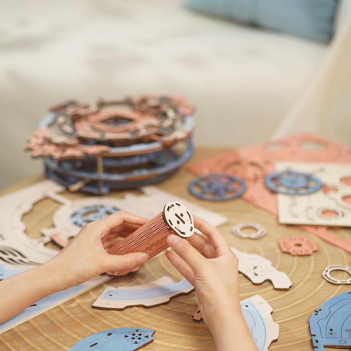 Hands sorting laser-cut wooden discs and clock components on a table during ROKR Romantic Note Wall Clock assembly