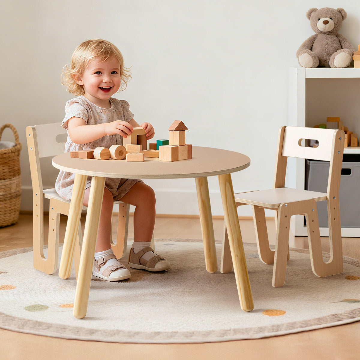 Laughing toddler builds with wooden blocks at the ROBUD natural beech round table and matching white chair set.