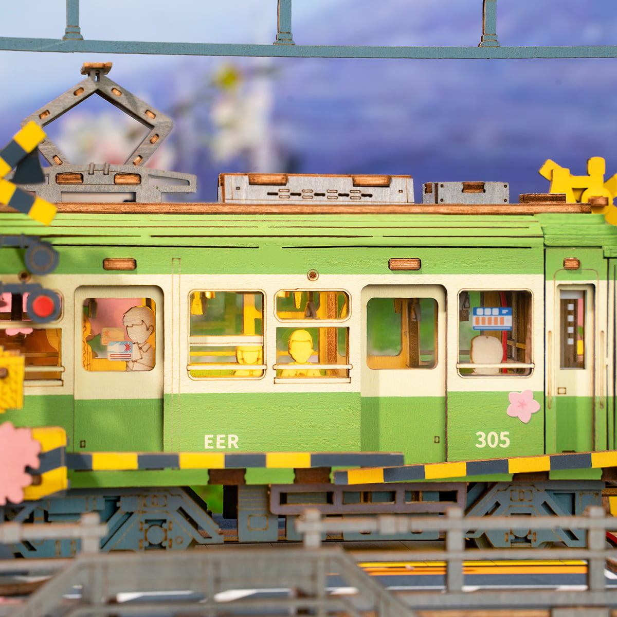 Side view of Rolife Sakura Journey green tram numbered 305 with miniature figures in illuminated carriage windows