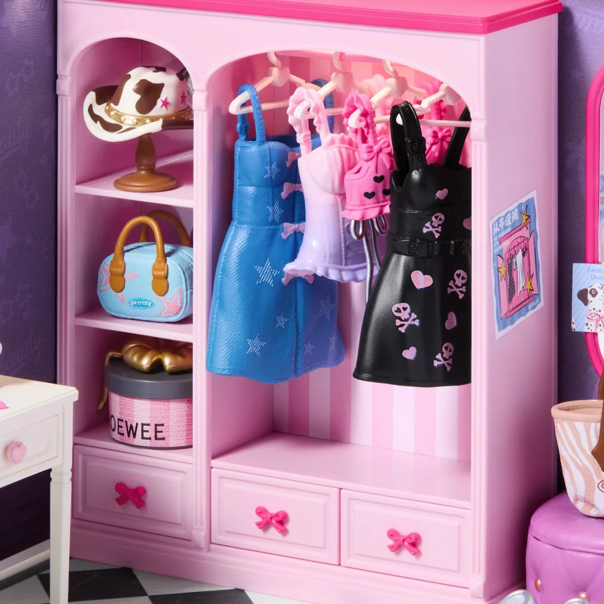 Rosa Miniatur-Kleiderschrank mit blauen, rosa und schwarzen Kleidern, Regalfächern mit Hut im Kuhmuster, blauer Handtasche und runder Schachtel sowie Schubladen mit rosa Schleifengriffen.