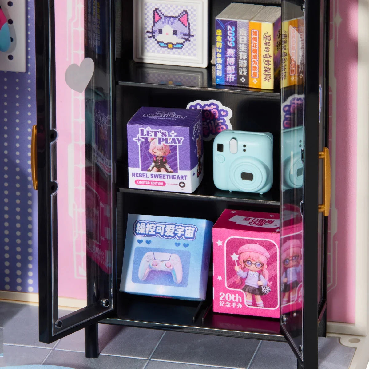 Schwarze Miniatur-Vitrine mit Glastüren und goldfarbenen Griffen; in den Fächern stehen kleine Schachteln, ein Pixel-Katzenbild, Bücher und eine mintgrüne Sofortbildkamera.
