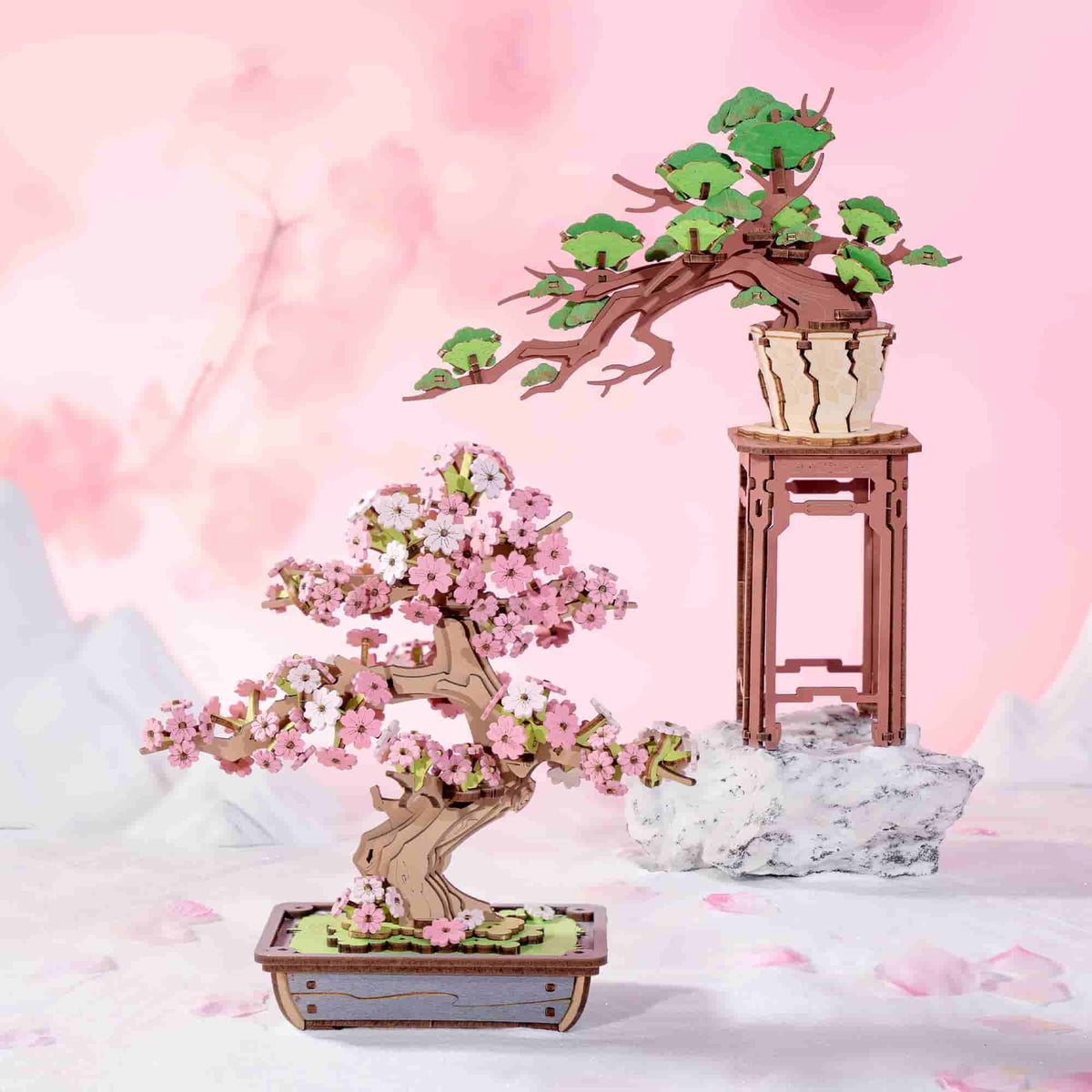 Rolife Sakura Bonsai TG415 and Evergreen Pine TG510 bonsai wooden puzzles side by side on soft pink background
