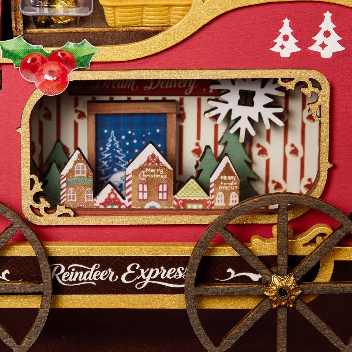Nahaufnahme der roten Schlittenseitenwand mit goldener Einfassung, Stechpalme, Fenster mit Miniaturdorfszene und der Aufschrift Reindeer Express.
