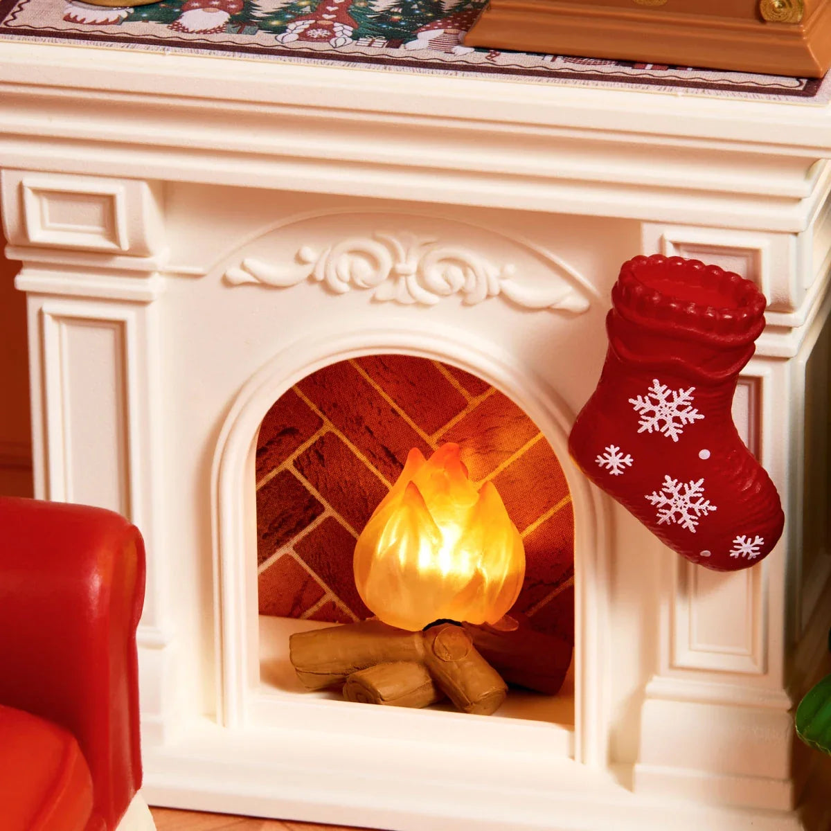 Nahaufnahme eines weißen Miniaturkamins mit leuchtender orangefarbener Flamme, Holzscheiten und rotem Schneeflockenstrumpf.
