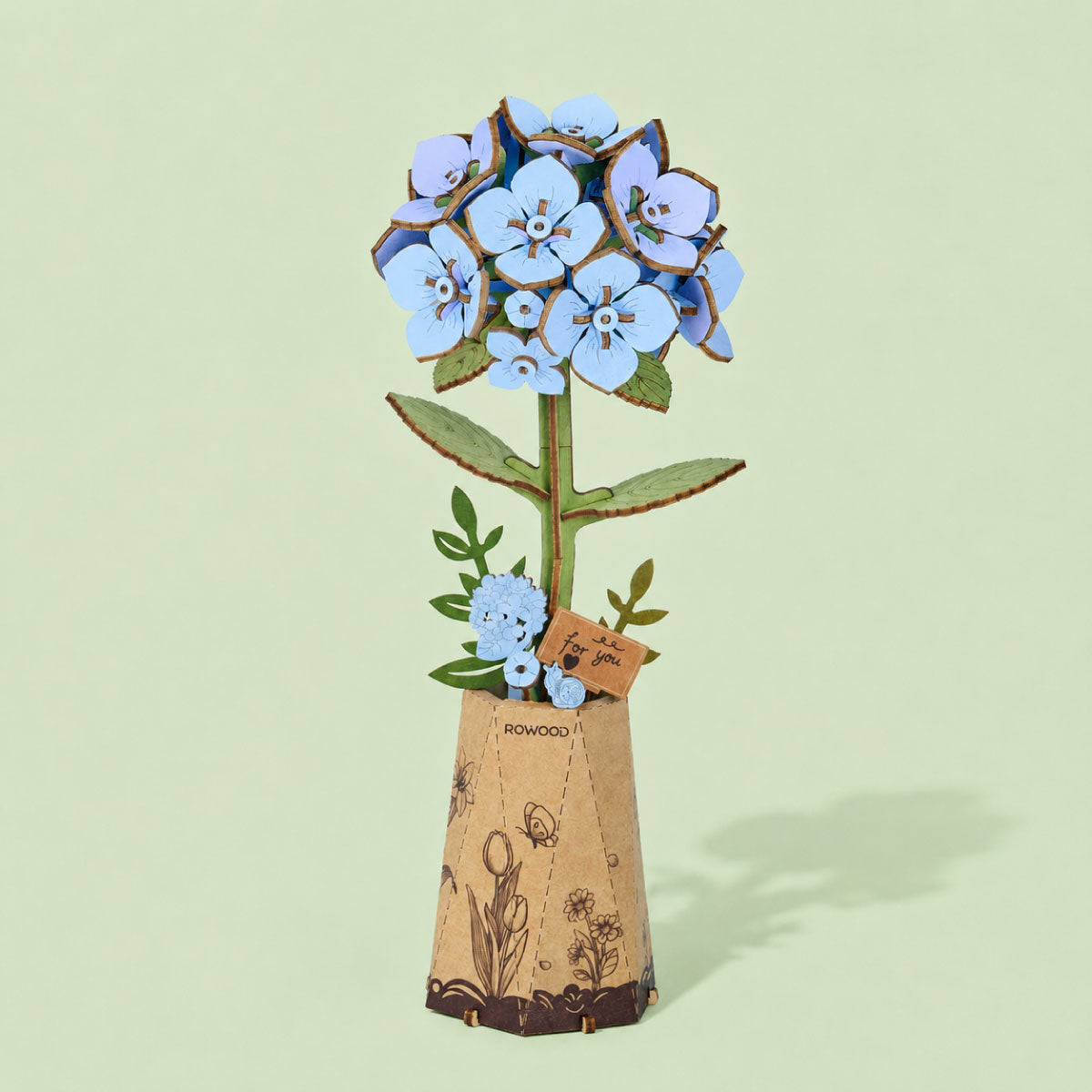 Blue wooden hydrangea in a tall cork patterned pot against a pale green background