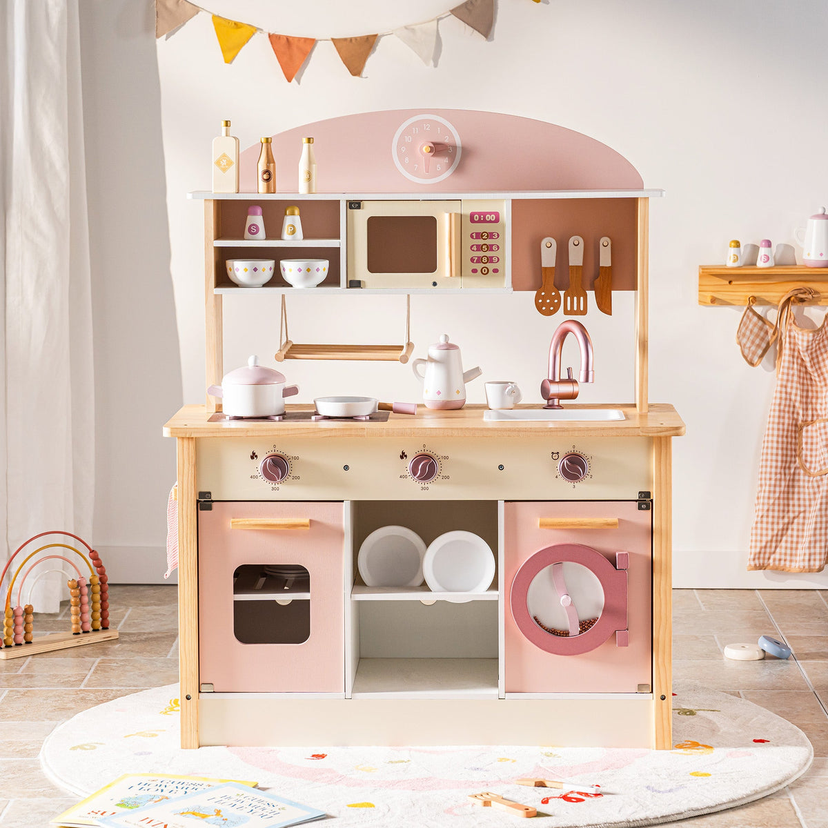 ROBUD Pink Wooden Kitchen PlaySet main kitchen counter with stove, sink and upper shelving in warm playroom light