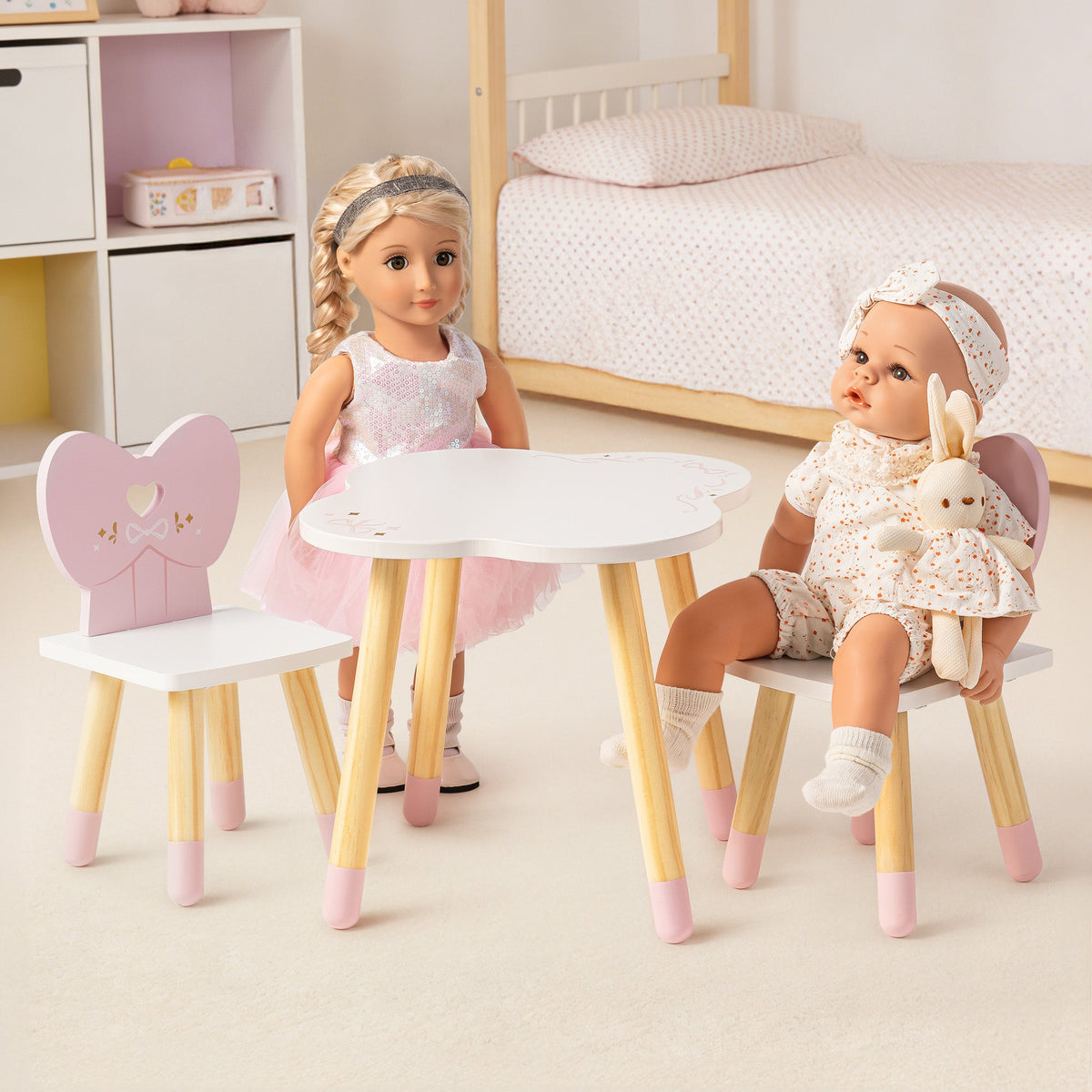ROBUD white and pink doll table set with two heart-back chairs styled in a child's bedroom with natural wood legs and pink accents