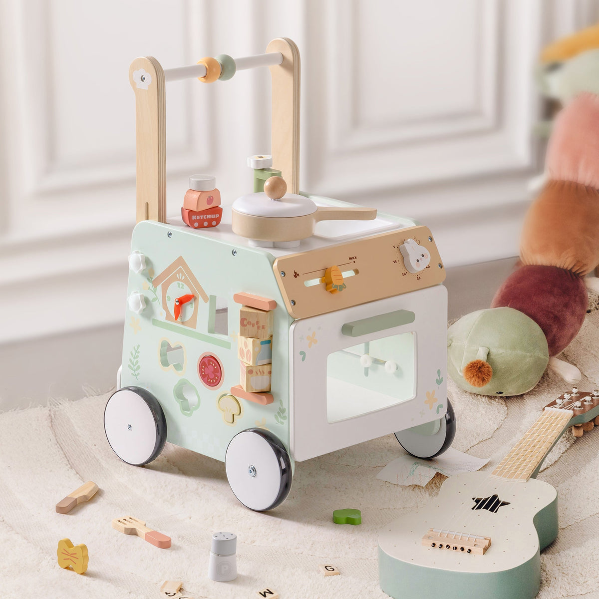 ROBUD Spring Countryside green baby push walker photographed from above in a playroom setting beside toy guitar, food accessories and plush animals