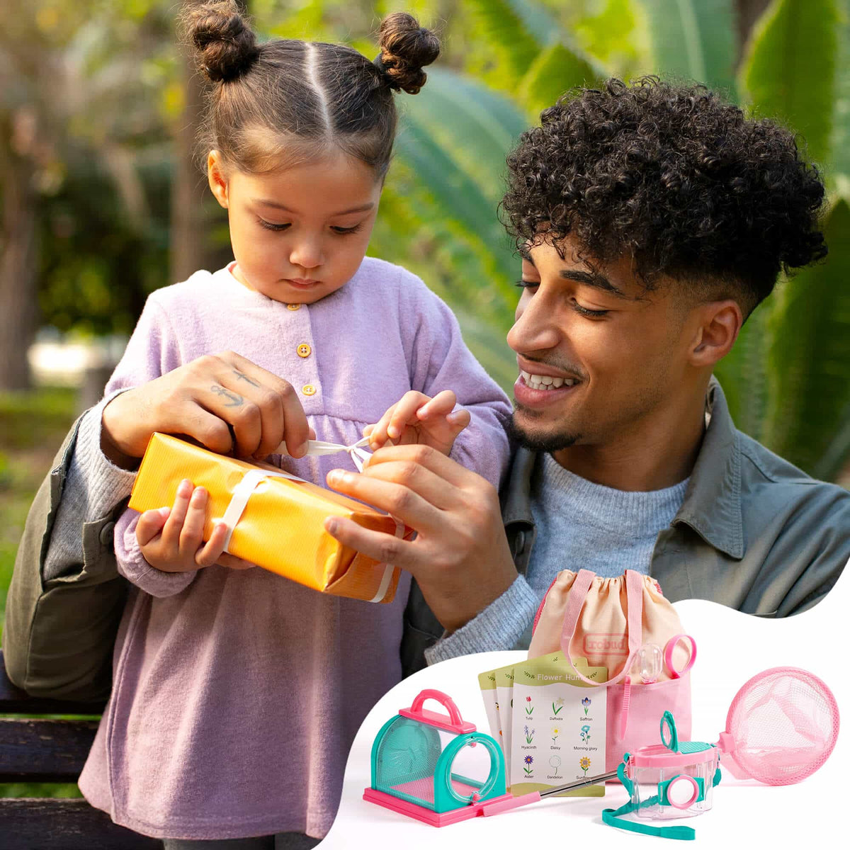 Father and daughter unwrapping the ROBUD outdoor kids explorer kit in pink, with bug catcher cage, magnifying jar, net, and leaf hunt card set visible in foreground