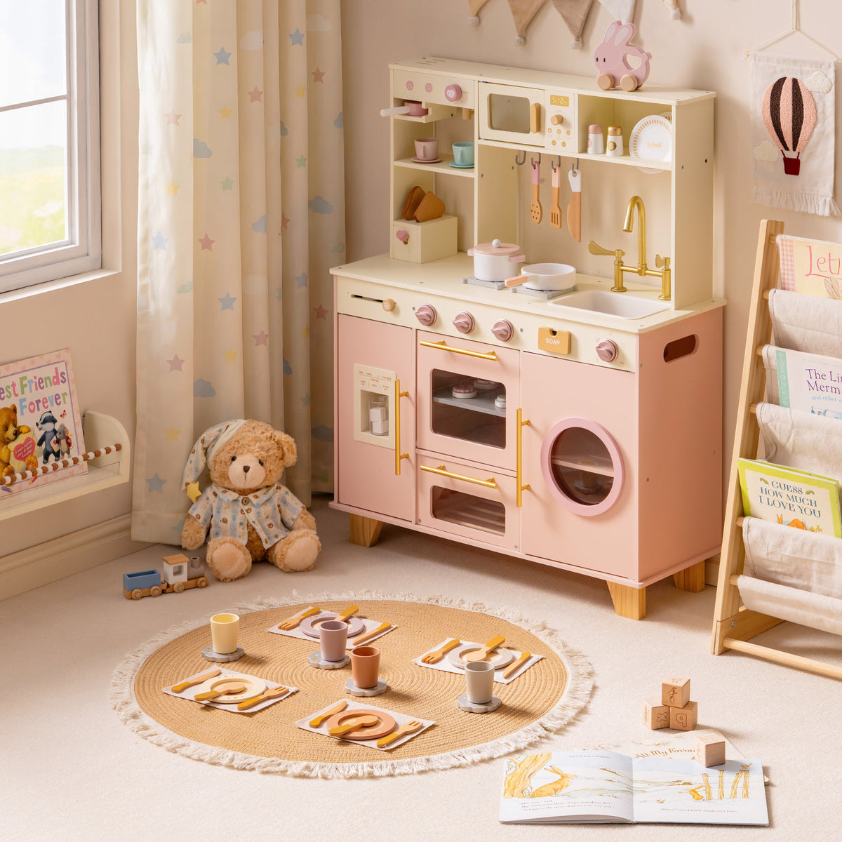 Side angle of the ROBUD Glowwood pink toy kitchen showing the washer drum, hanging utensils, and gold-toned faucet detail.