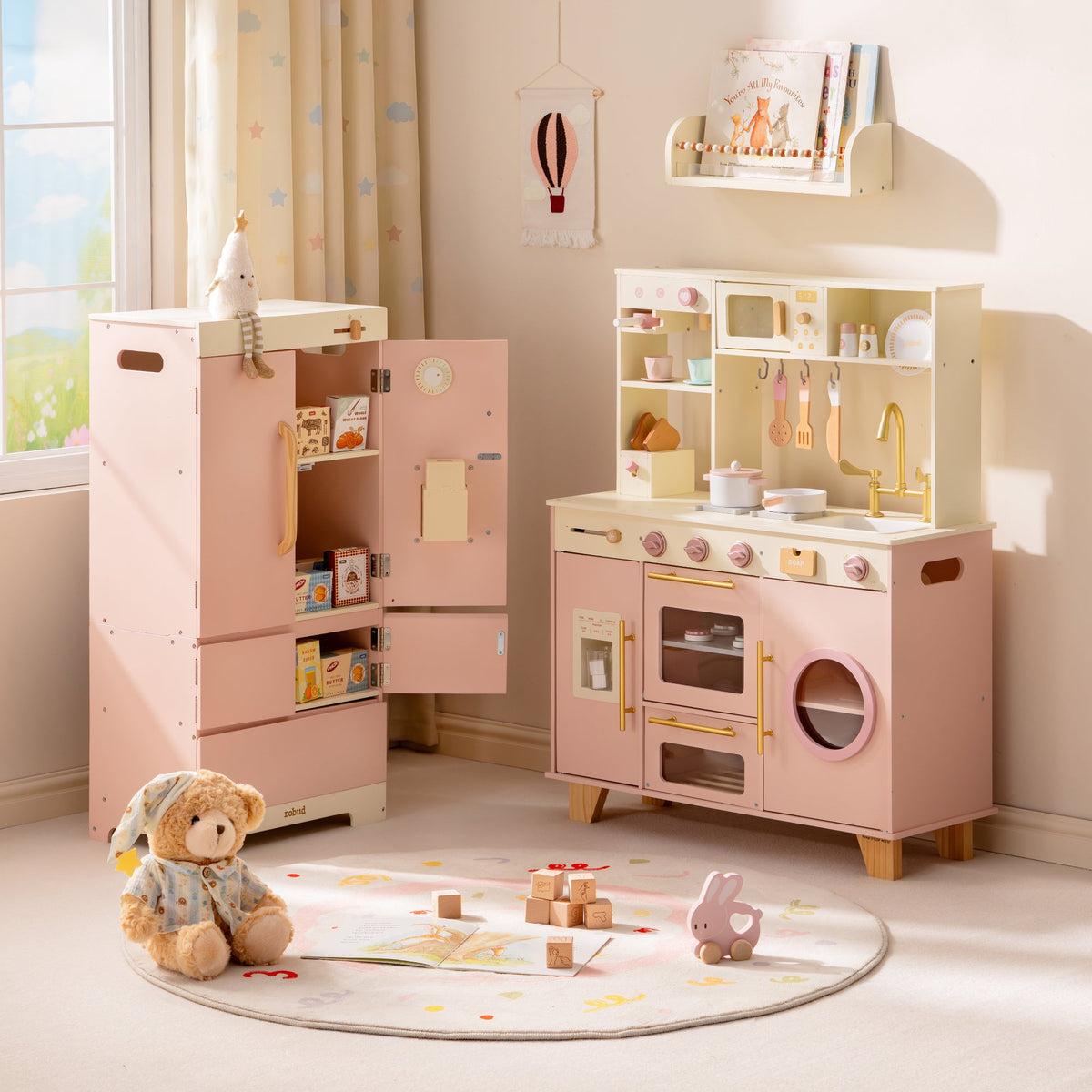 ROBUD Glowwood pink toy refrigerator next to the play kitchen, both with open shelving, shown in a tidy pastel playroom.