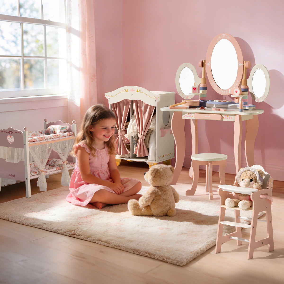 Girl in pink dress sits on the floor with a teddy bear surrounded by the full ROBUD princess play furniture collection.
