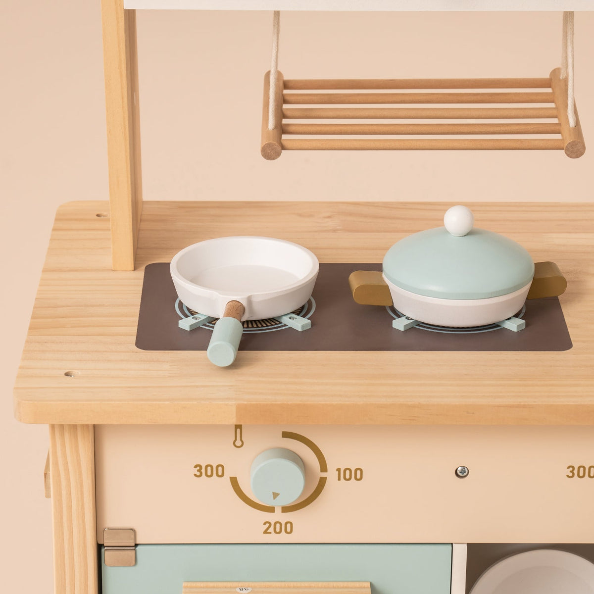 ROBUD kitchen stovetop close-up showing round frying pan and lidded pot on a dark cooktop with temperature dial below