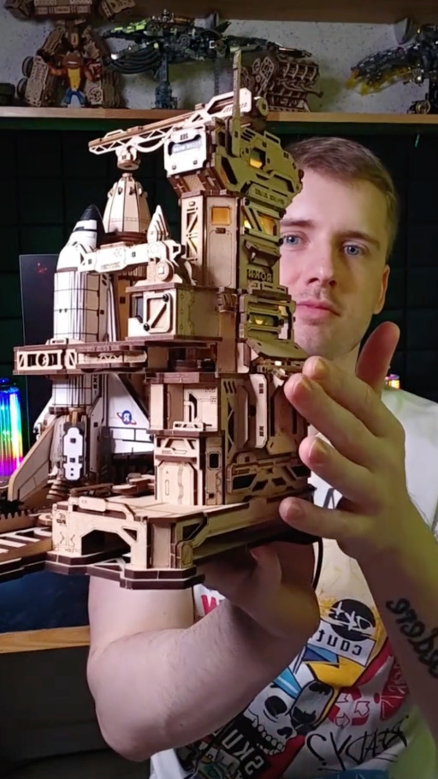 Man holding a tall wooden sailing ship model with white sails and a detailed deck