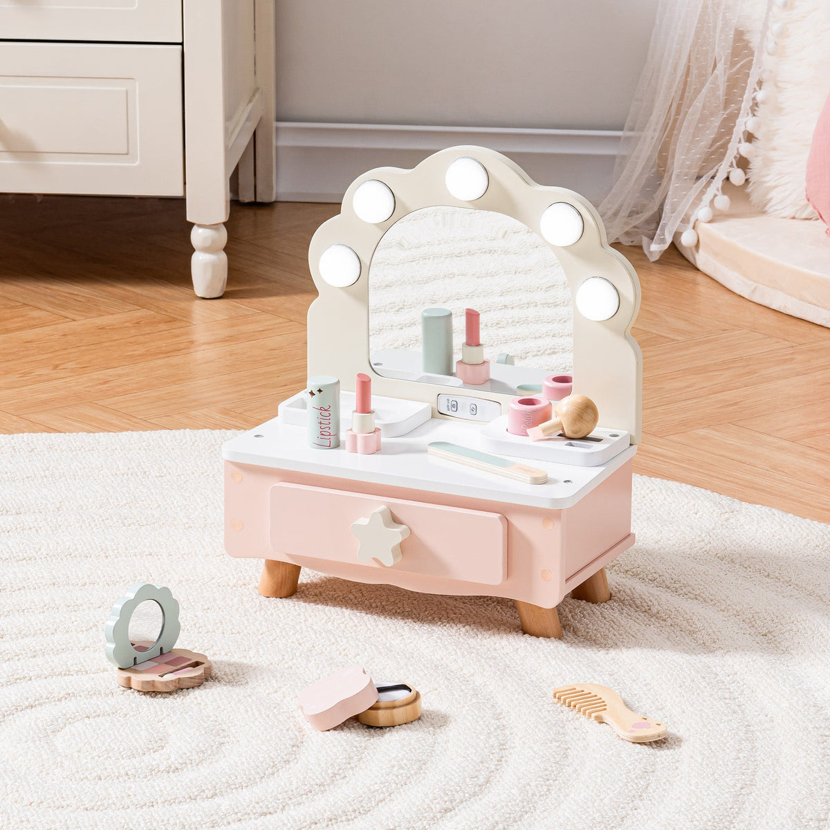 ROBUD pink wooden tabletop vanity on a white shag rug with wooden play makeup accessories scattered around the base.